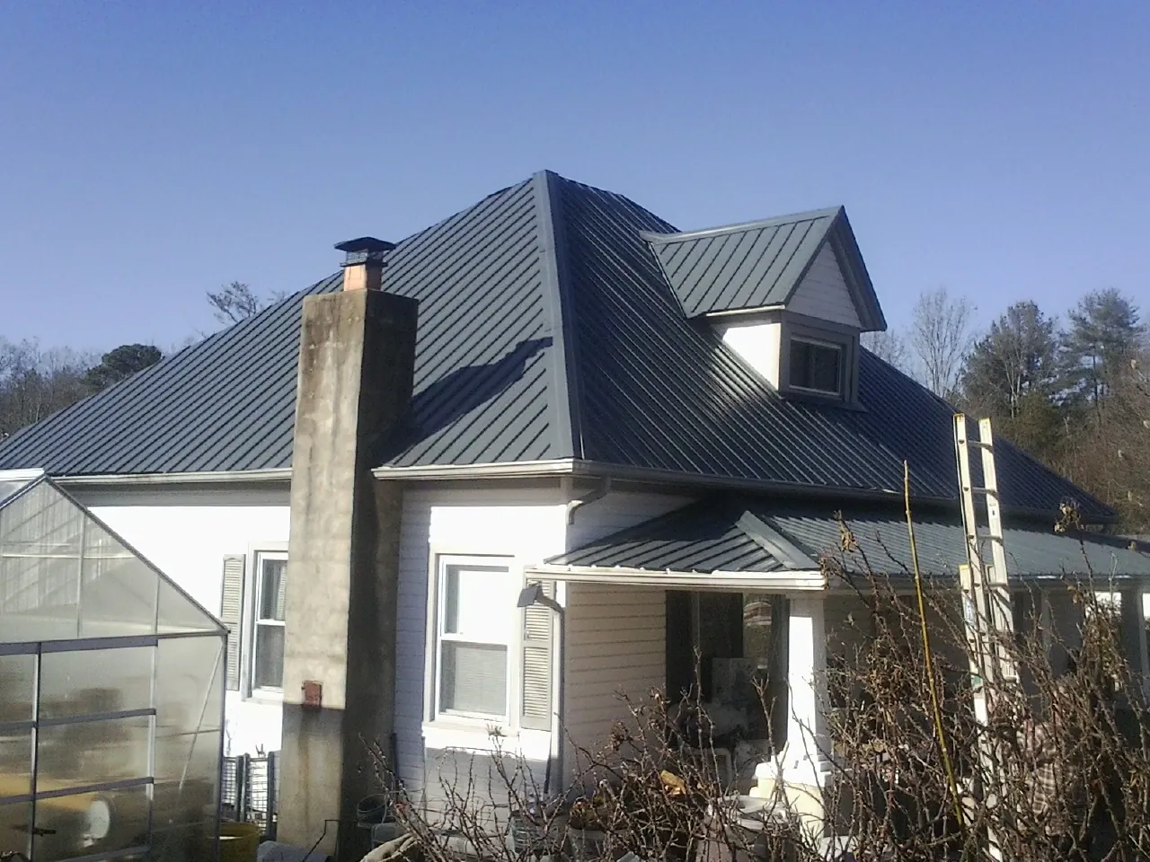Dark blue standing seam metal roof on a white farmhouse with dormer — Slate & Tile Roof Repair by Roofing Brothers in Mccloud