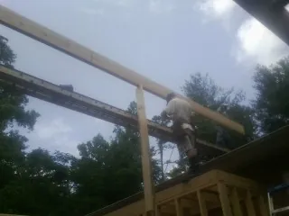 Carpenter setting a ridge beam over a new addition frame — Ice Dam Removal by Roofing Brothers in Mccloud