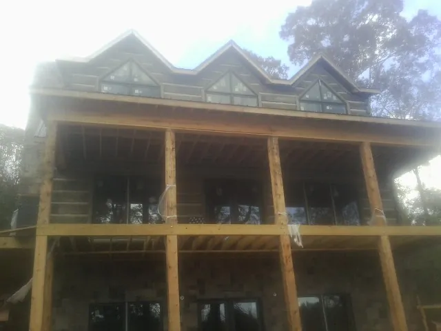 Dormers and porch framing on a large log home under construction — Roof Coating work by our crew in Mccloud