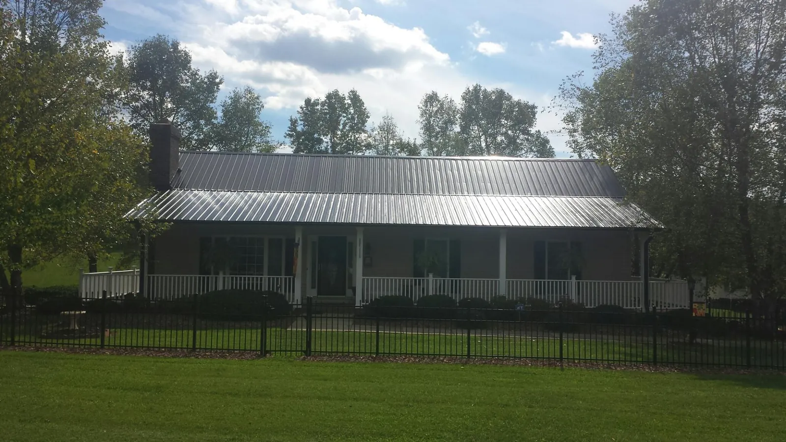 Gray metal roof on a brick ranch with a full width front porch — Gutter Guard Installation work by our crew in Mccloud