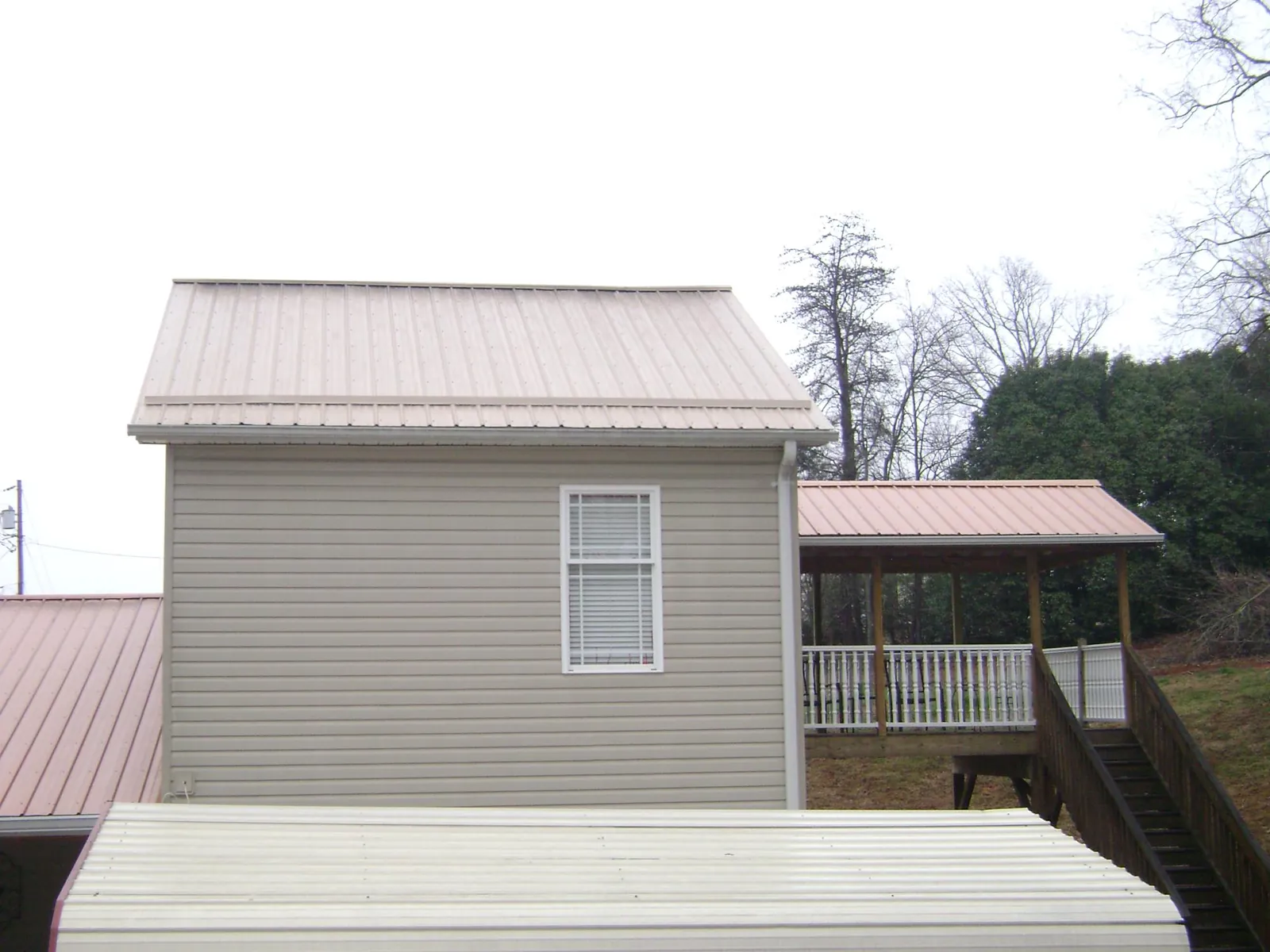 Tan metal roofs on a two story addition and attached porch, from a Roof Replacement job in Mccloud